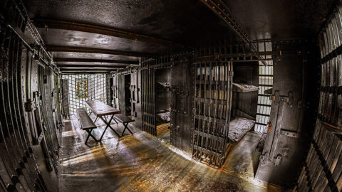 interior shot of the Old Jail featuring open cells with beds and a picnic table