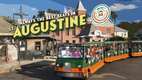 St. Augustine trolley in front of the Old Jail and the words 'Always the best seats in St. Augustine - Now that's Transportainment'